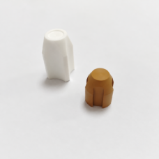 White and brown shaped valve components with longitudinal ribs.
