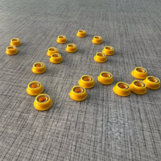 Small yellow flanged seals with visible internal springs on a textured surface.