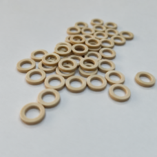 Beige flat annular gaskets scattered on a pale surface.