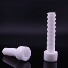 Two white PTFE socket-head screws on a dark reflective surface, one horizontal with its hexagonal socket visible and one upright.