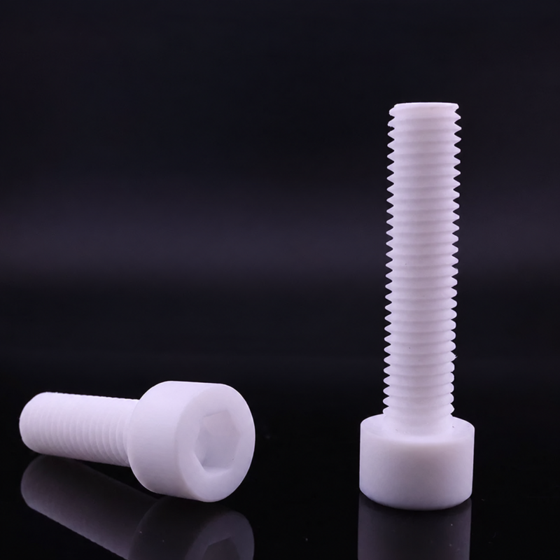 Two white PTFE socket-head screws on a dark reflective surface, one horizontal with its hexagonal socket visible and one upright.