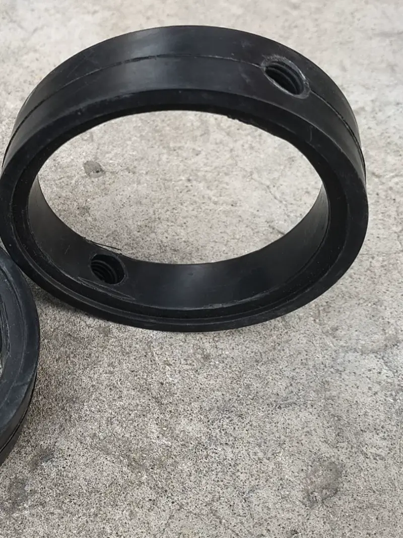 Black butterfly valve seal with visible stem openings on a gray textured floor; another black seal is partially visible at the left edge. Supplied by IKSONIC in China.