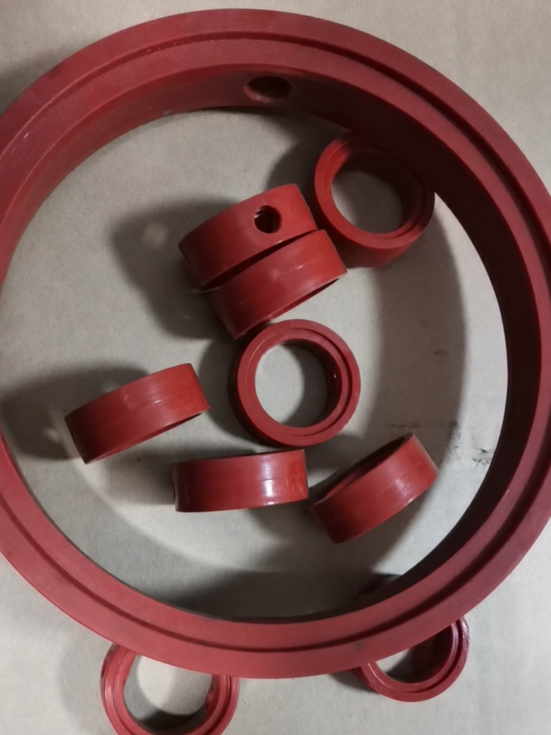 Red butterfly valve seal assortment in multiple sizes on the original gray floor, including a large outer seal and smaller seals. Supplied by IKSONIC in China.