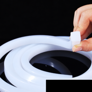 White IKSONIC solid square silicone strip coiled on a black background, with its square cut end held between fingers.
