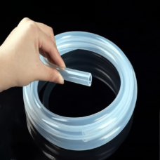 Hand holding the open end of clear silicone hose above a coil on a black background.