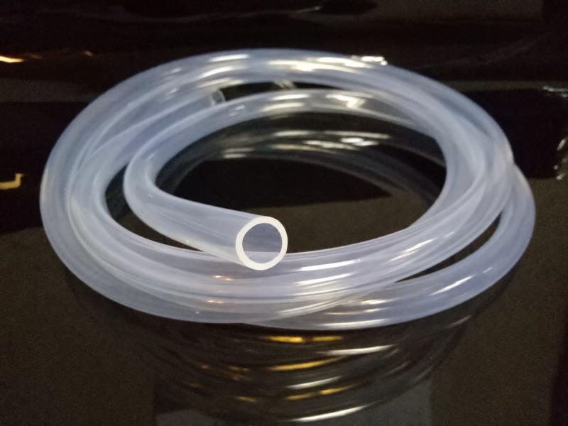 Coiled transparent silicone tubing with a visible hollow cut end, supplied by IKSONIC in China.