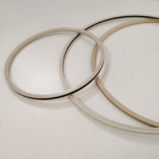 Overlapping beige annular sealing rings with narrow dark inner edges on a pale surface.