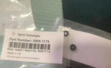 Two small black annular seals visible through clear packaging beside the original English product label.