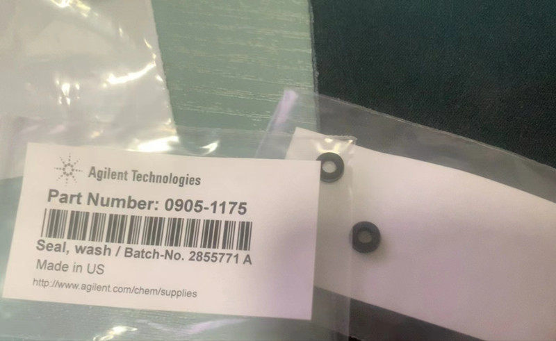 Two small black annular seals visible through clear packaging beside the original English product label.