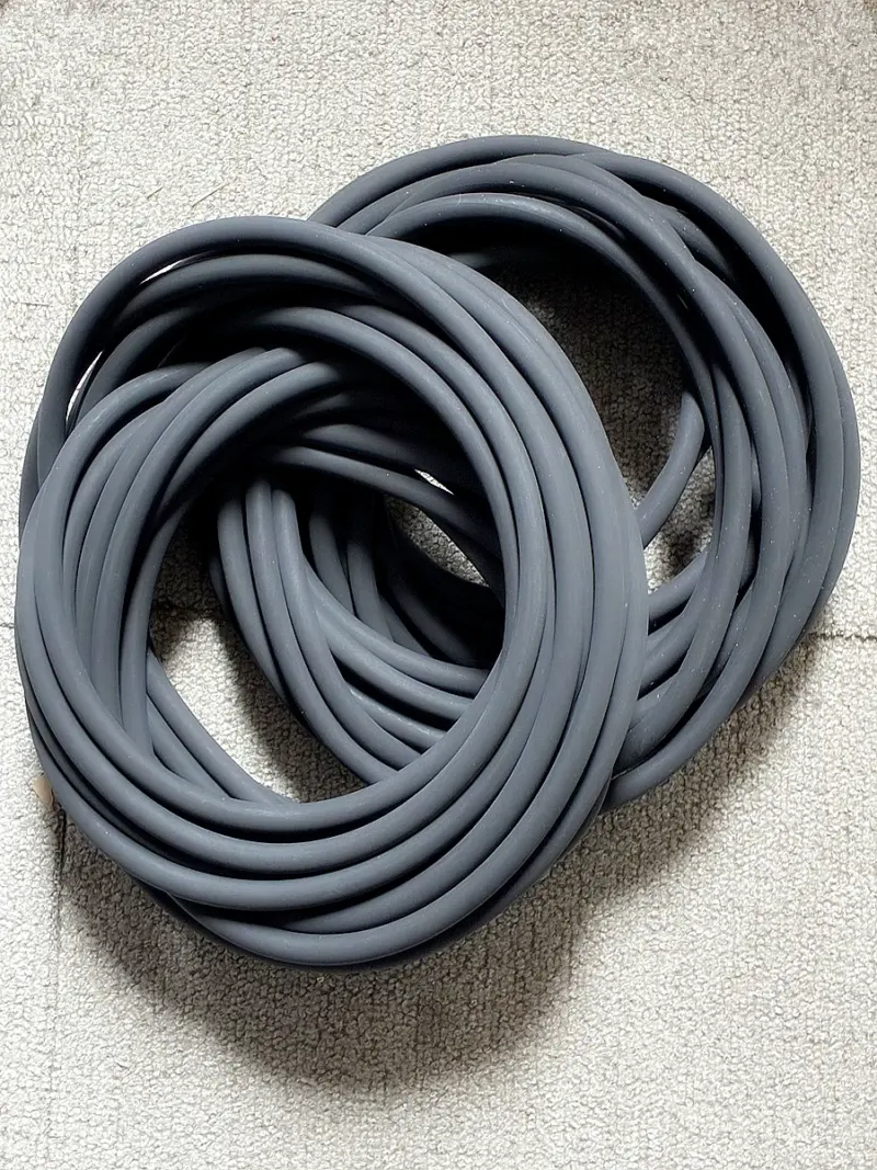 Overlapping dark round-section O-rings on a textured pale surface.