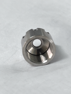 Close-up of a metal nozzle cap showing internal threads, a conical inner face and a central opening.