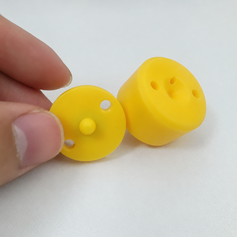 Yellow diaphragm held beside a yellow cylindrical valve body, showing the center pin and mounting holes.