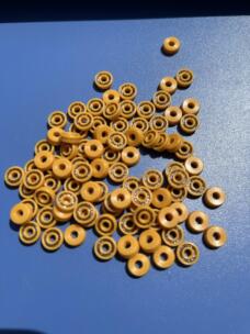 Small yellow annular seals with visible metal spring elements on a blue surface.
