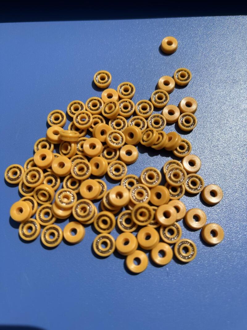 Imported Dispensing Valve Seals - V-Spring Size Options Small yellow annular seals with visible metal spring elements on a blue surface.