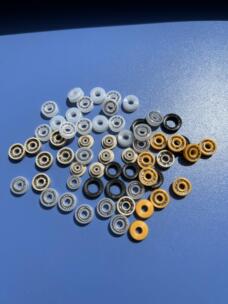 White, beige, yellow and black annular dispensing valve seals with visible metal spring inserts on a blue surface.