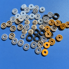 Small dispensing valve spring-energized seals in white, beige, yellow and black with visible springs.