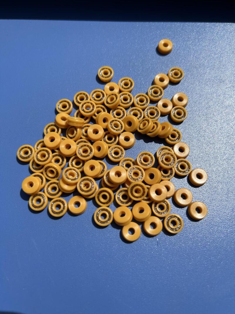 Yellow dispensing valve spring-energized seals with visible metal springs on a blue surface.