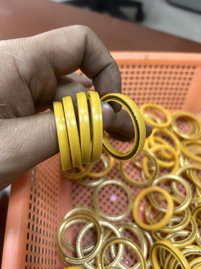 Hand holding yellow sealing rings above an orange basket, showing the ring edges and exposed metal spring.
