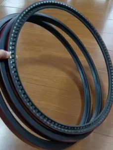 Large dark grinding roller shaft seals held over a wood-patterned floor