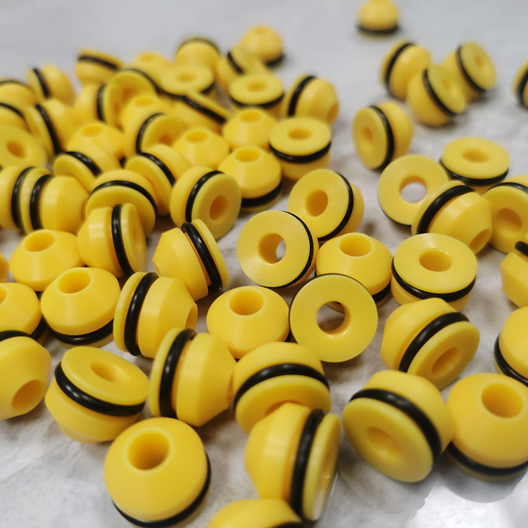 Yellow spool-shaped nozzle seals with black outer rings arranged on a pale surface.