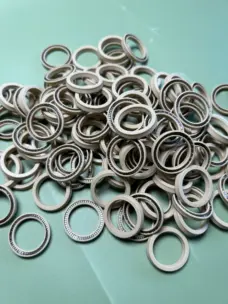 Beige ice machine shaft seals with visible metal springs piled on a green surface
