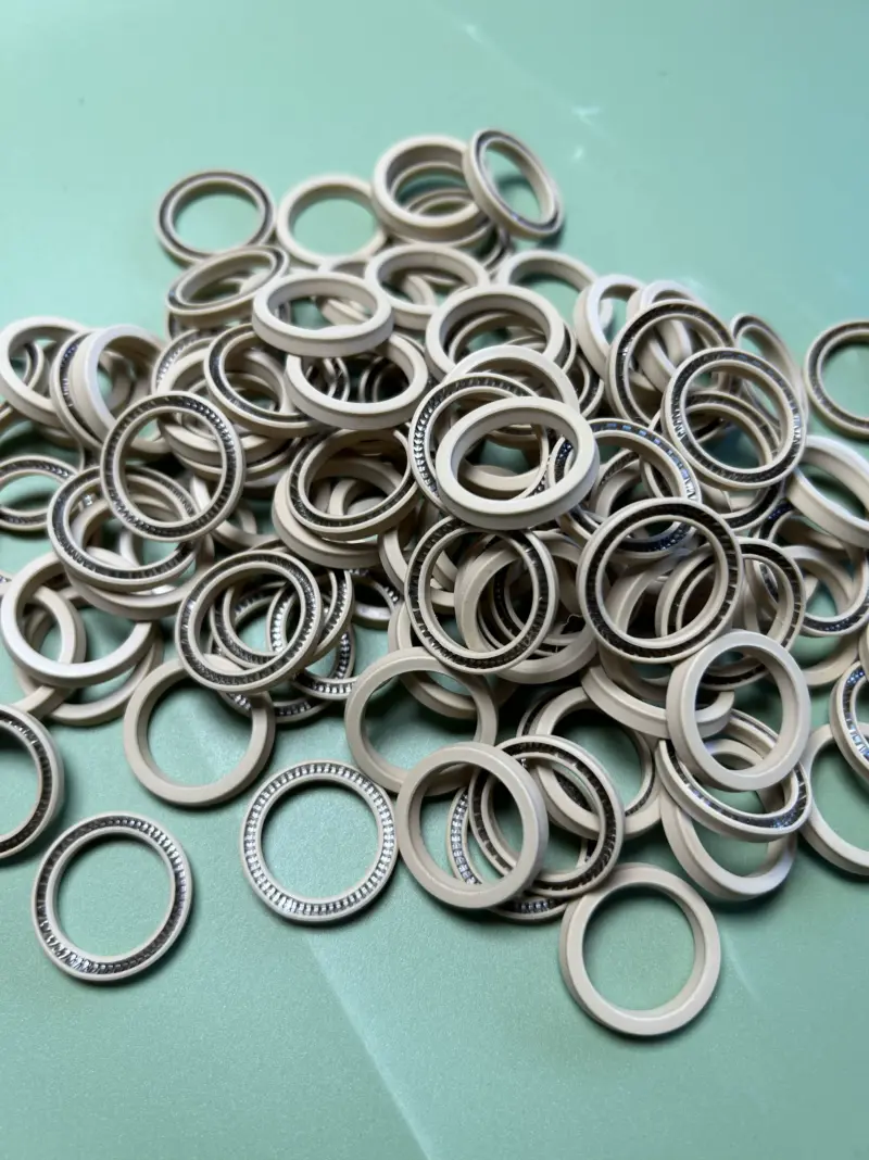 Ice machine rotary shaft seals Beige ice machine shaft seals with visible metal springs piled on a green surface