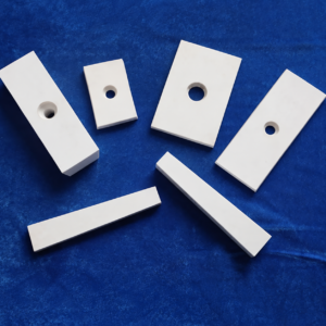 Four drilled white IKSONIC ceramic liner plates and two solid strips on blue fabric.