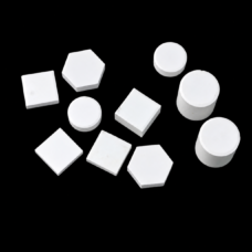 White IKSONIC ceramic square and hexagonal tiles, round discs and cylindrical pieces arranged on a black background.