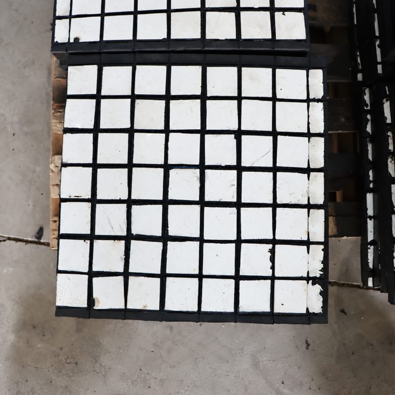 Close view of white square ceramic tiles and black joints on an IKSONIC liner panel.