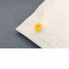 Supplier photograph of one yellow analyzer plunger seal showing its flat back face and center opening on a white cloth.