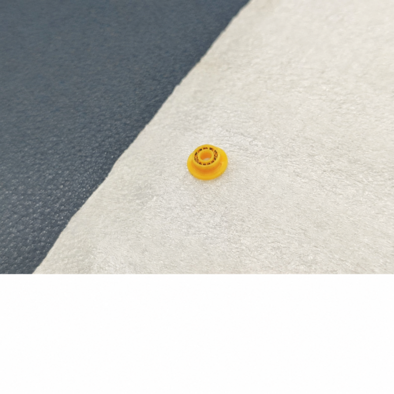 iksonic-analyzer-plunger-seal-front-view Supplier photograph of one yellow analyzer plunger seal with a raised center and visible small ring details on a white cloth.