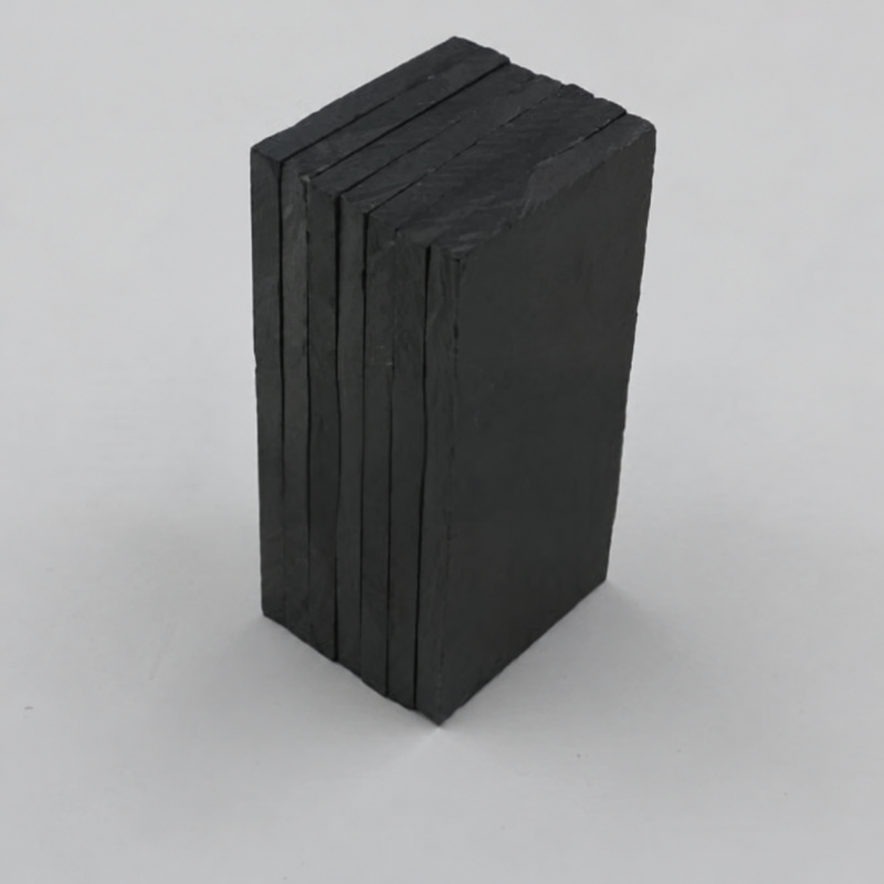 Stacked dark rectangular IKSONIC ceramic liner tiles showing their edges and surface texture.