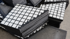 Overlapping IKSONIC ceramic rubber liner panels showing white tiles and thick dark backing edges.