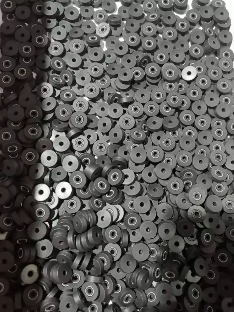 IKSONIC adhesive module seals - China supplier A pile of small dark flanged seals, many with visible internal springs; supplied by IKSONIC in China.