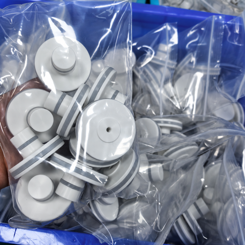 White piston-shaped valve parts with grey circumferential bands packed in clear bags inside a blue box; supplied by IKSONIC in China.