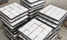 Stacked IKSONIC composite ceramic liner panels with white square tiles and dark panel edges.