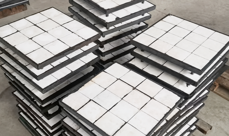 Stacked IKSONIC composite ceramic liner panels with white square tiles and dark panel edges.