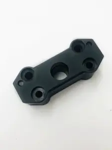 Close view of an IKSONIC black door belt clamp showing its central opening and four mounting holes.