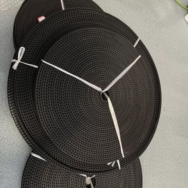 Coiled black IKSONIC elevator door timing belts arranged in rolls.