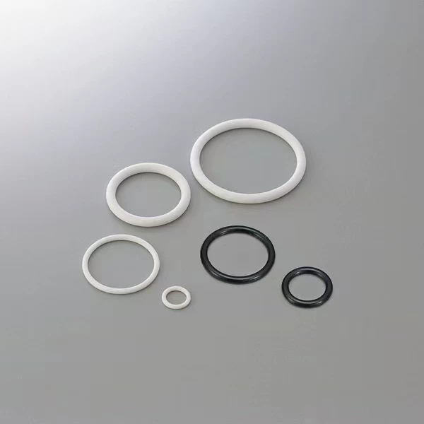 iksonic-ffkm-o-rings-supplier-00-black-and-white-rings Six black and white FFKM O-rings in assorted sizes on a gray surface, supplied by IKSONIC in China.