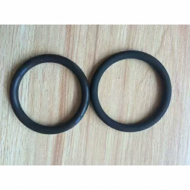 Two black FFKM O-rings side by side on a light wood surface, IKSONIC sealing product example.