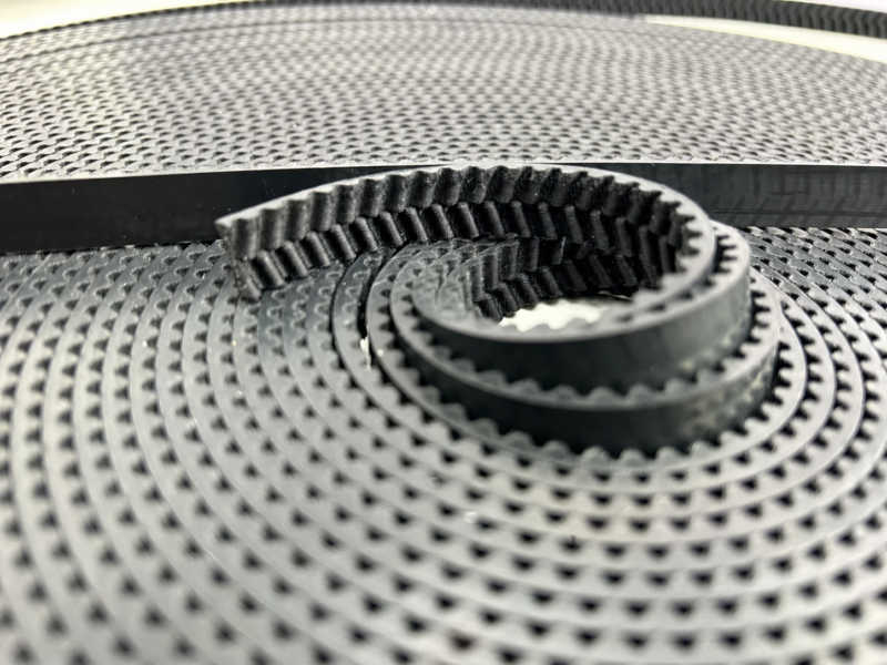 Curved open end of a black herringbone elevator door belt on a coil, IKSONIC wholesale supply.