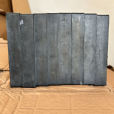 Dark rectangular IKSONIC ceramic liner tiles standing side by side on cardboard.