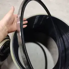 Large IKSONIC metal-cased rotary oil seal held by hand, with additional seals visible behind it.