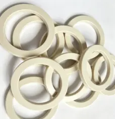 Reverse faces and angled profiles of cream-colored PEEK seals from IKSONIC.