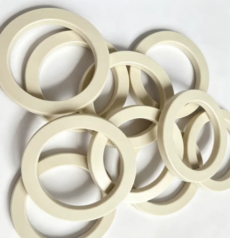 Reverse faces and angled profiles of cream-colored PEEK seals from IKSONIC.