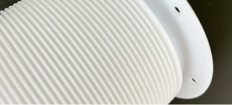 White PTFE bellows close-up showing corrugations and mounting holes in the end flange; supplied by IKSONIC in China.
