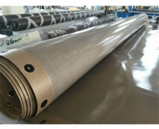 Rolled PTFE-coated conveyor belt showing layered fabric and black edge eyelets.