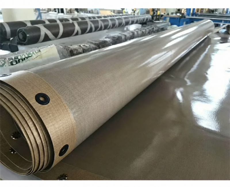 iksonic-ptfe-coated-conveyor-belt-roll-eyelets Rolled PTFE-coated conveyor belt showing layered fabric and black edge eyelets.