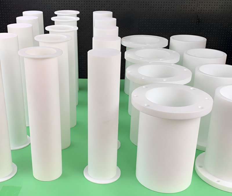 IKSONIC PTFE cylindrical sleeves and flanged bushings - China supplier White PTFE cylindrical sleeves and flanged bushings displayed in rows on a green surface; supplied by IKSONIC in China.
